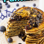 Stack of fluffy gluten-free blueberry pancakes topped with syrup and fresh blueberries